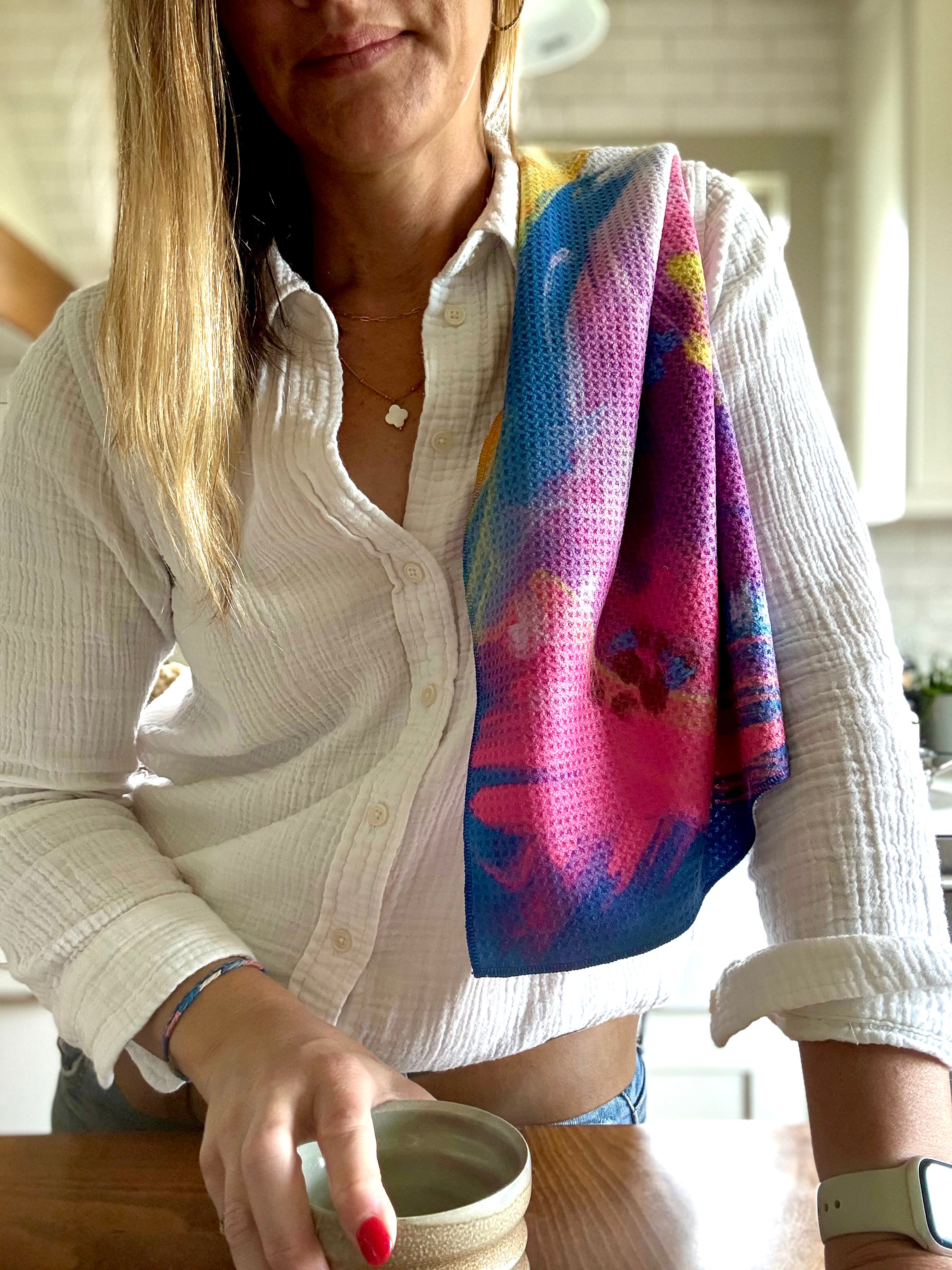 Colorful abstract floral quick-dry towel over a woman's shoulder in the kitchen. Bloom design is based on Isaiah 35:2.