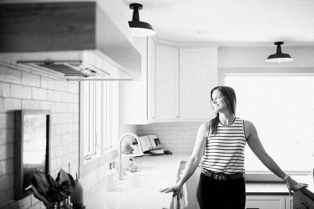 This mom is standing in her bright kitchen in front of the sink with 2 gratitude bottles. I'm sure she's smiling because the kitchen is clean.