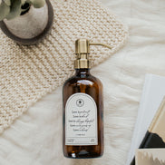 Amber glass Love Is... multipurpose Gratitude Bottle with gold pump on towels.