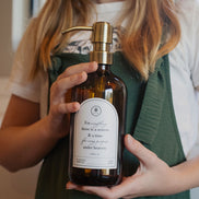 Child holding an amber glass Seasons multipurpose Gratitude Bottle with gold pump.