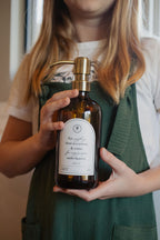 Child holding an amber glass Seasons multipurpose Gratitude Bottle with gold pump.