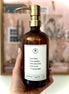 Hand holding an Amber glass I am Kind hand soap  Gratitude Bottle with gold pump.