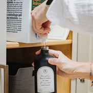 Refilling a black glass Seasons multipurpose Gratitude Bottle with hand soap.