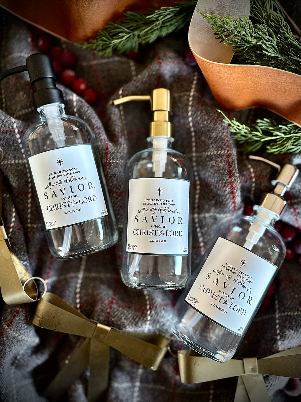 Reusable glass Christmas Gratitude Soap & lotion dispensers amongst Christmas decorations.