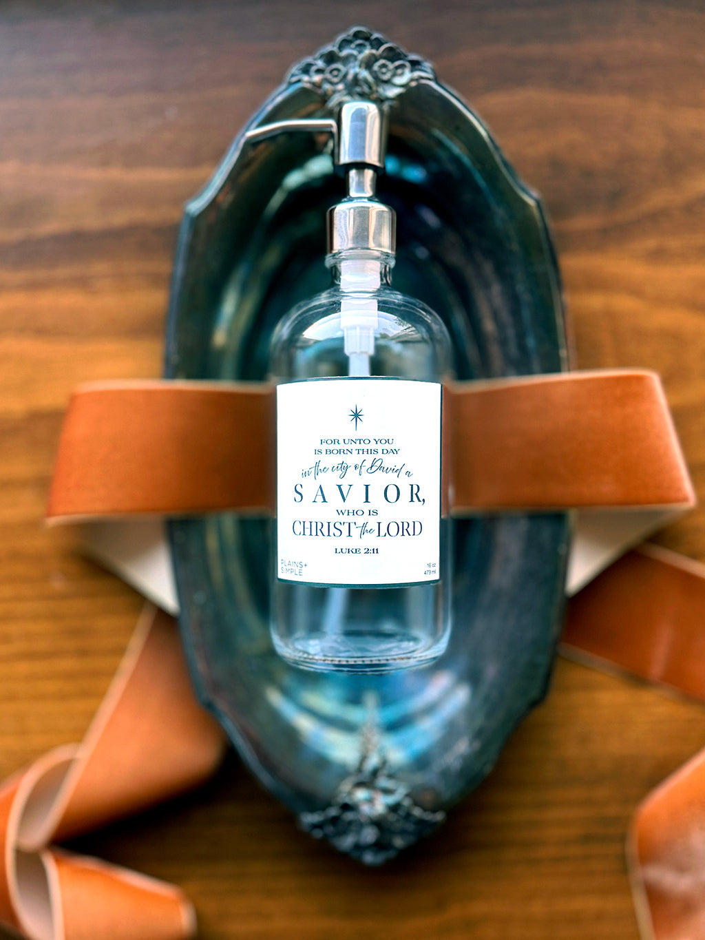 Reusable glass Christmas Gratitude Soap dispenser amongst Christmas decorations.